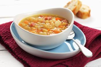 Bowl of soup with diced onion, carrots, potato and split peas 